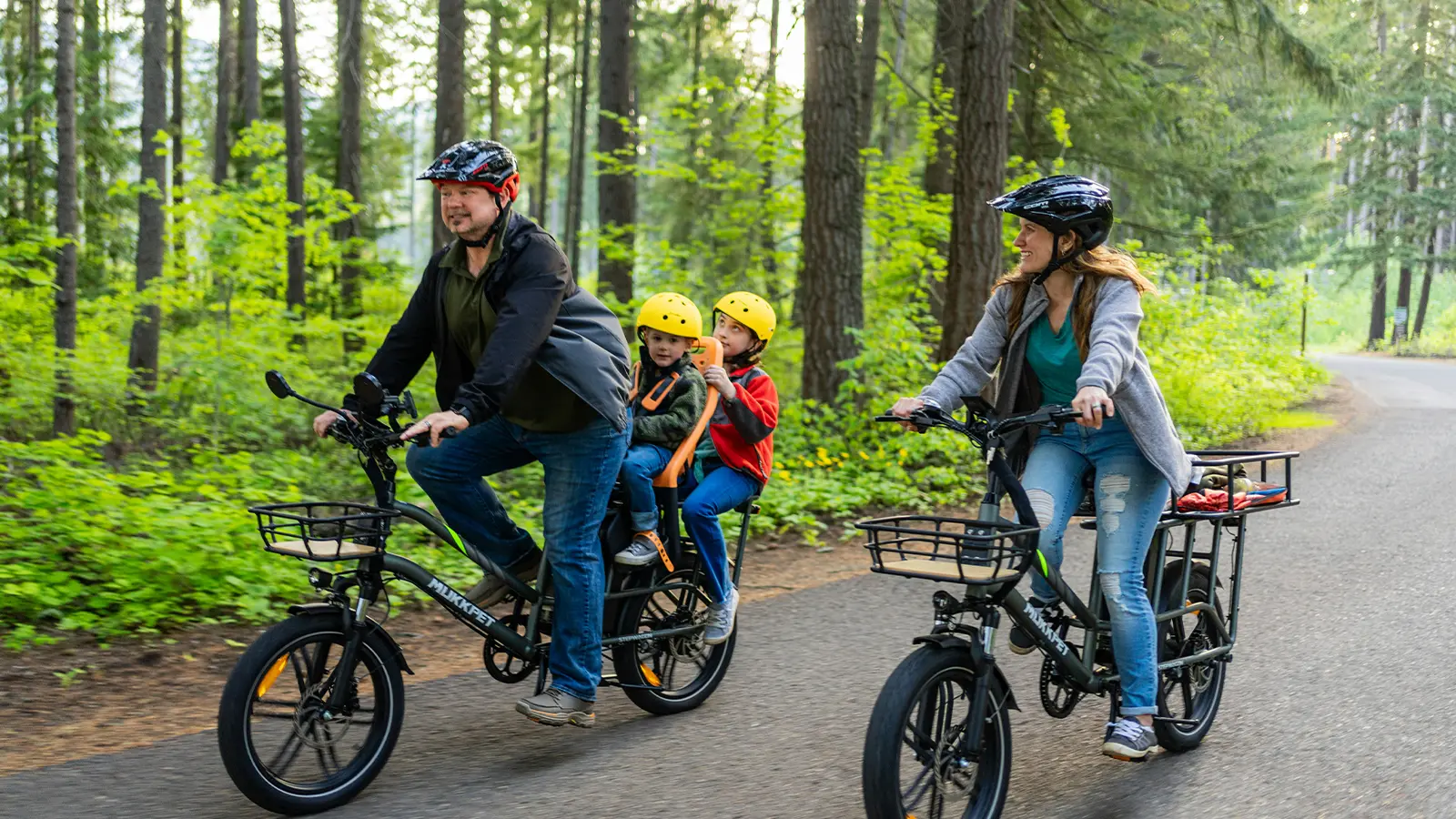 A family riding their e-bikes through a forest