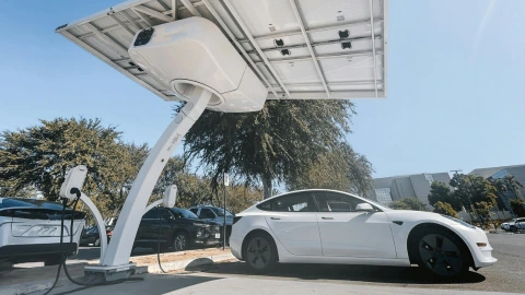 Tesla electric model s parked under large public solar EV charging panel