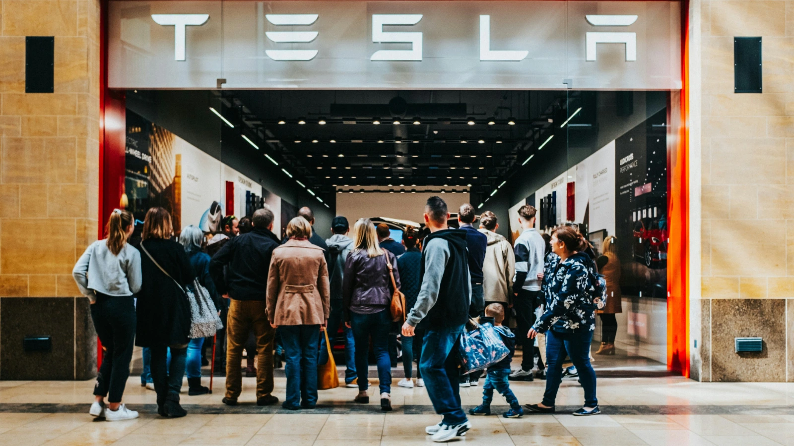 Crowd of people standing outside of a Tesla dealership waiting to order a vehicle online