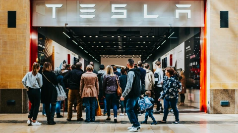 Crowd of people standing outside of a Tesla dealership waiting to order a vehicle online