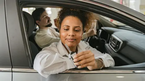 A woman considering a fuel-efficient vehicle purchase while sitting inside a car