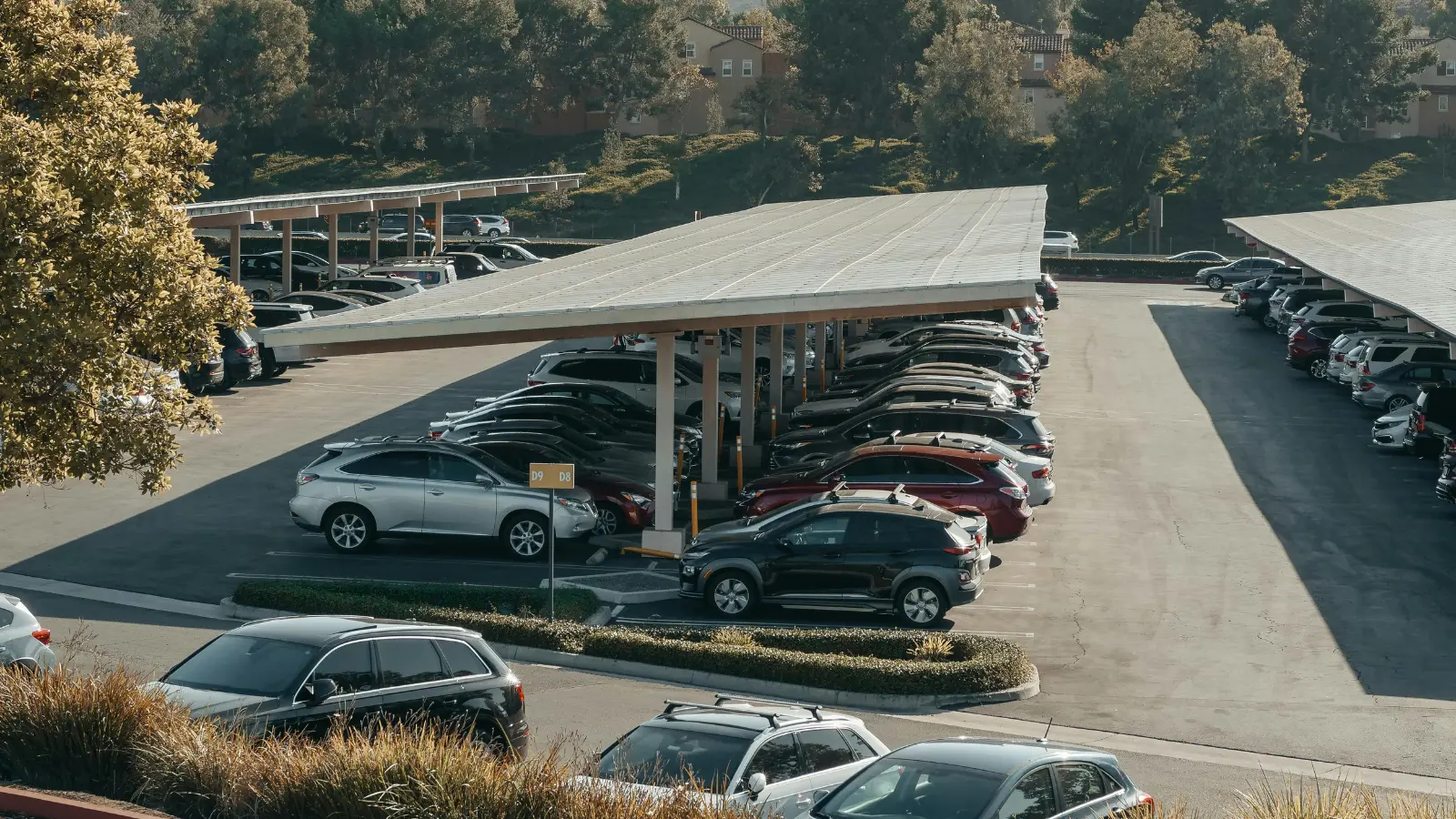 rows of green vehicles parked under solar panels