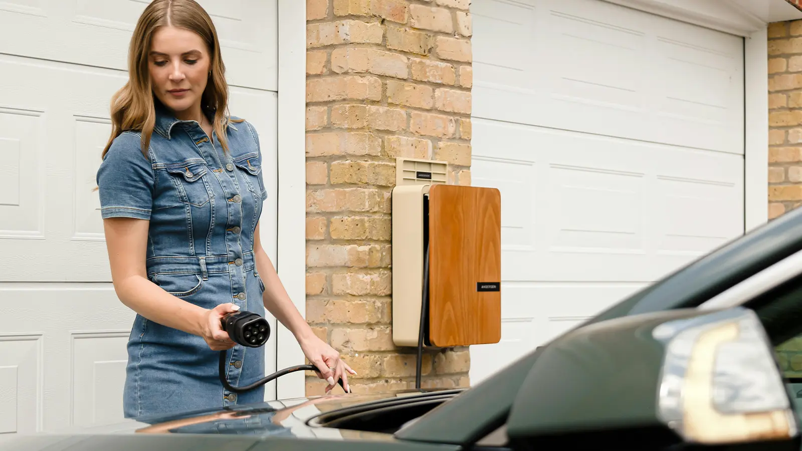 A women charging her EV vehicle at home on a sunny day