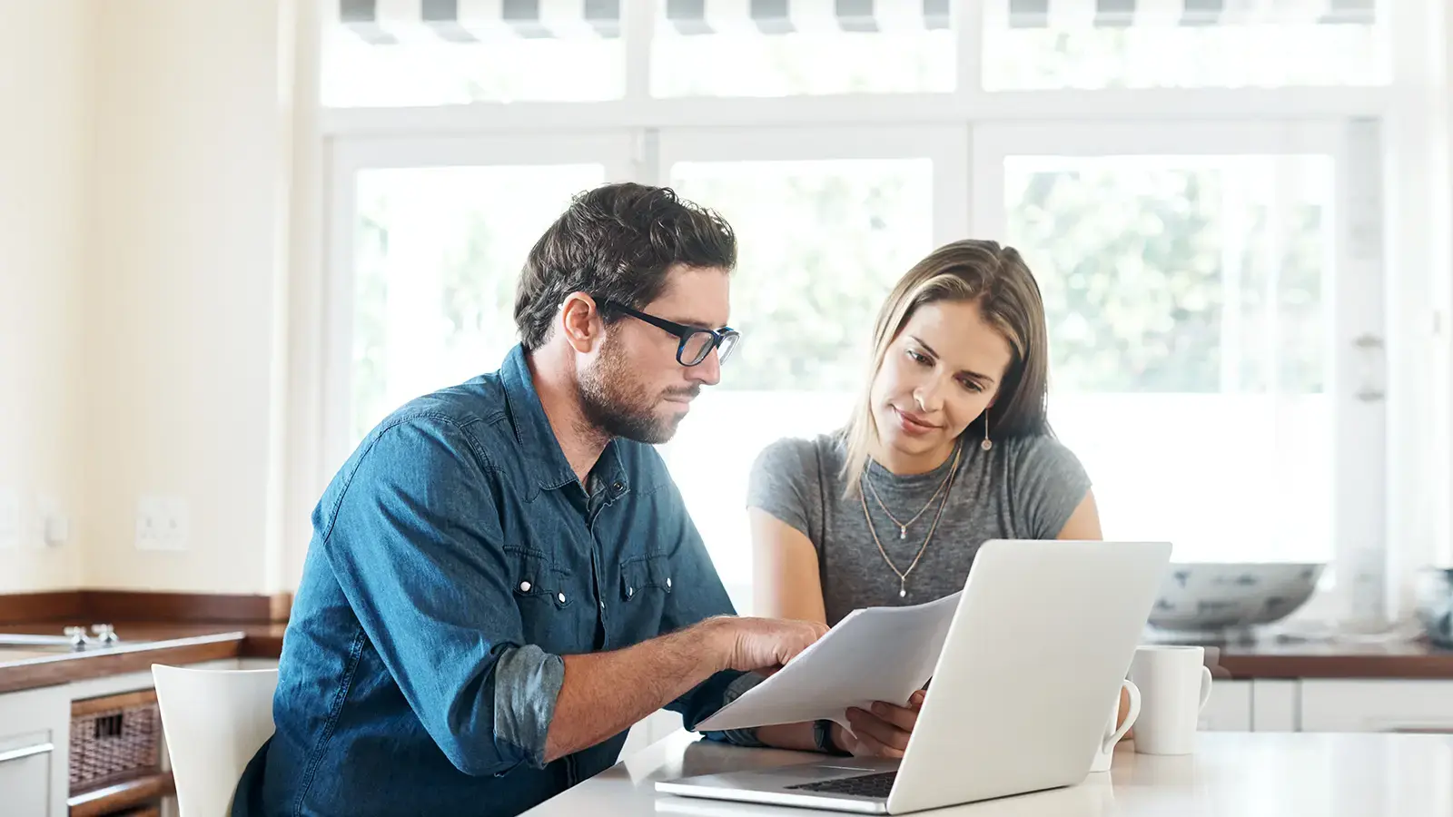Hombre y mujer sentados en un escritorio mirando una computadora clasificando archivos