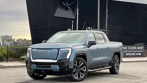 A blue GMC Sierra EV Denali on the bay next to the Queen Mary 