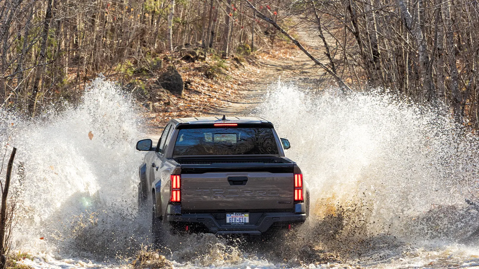 2025 Toyota Tacoma TRD Pro Hybrid off-roading with a epic water splash rear view