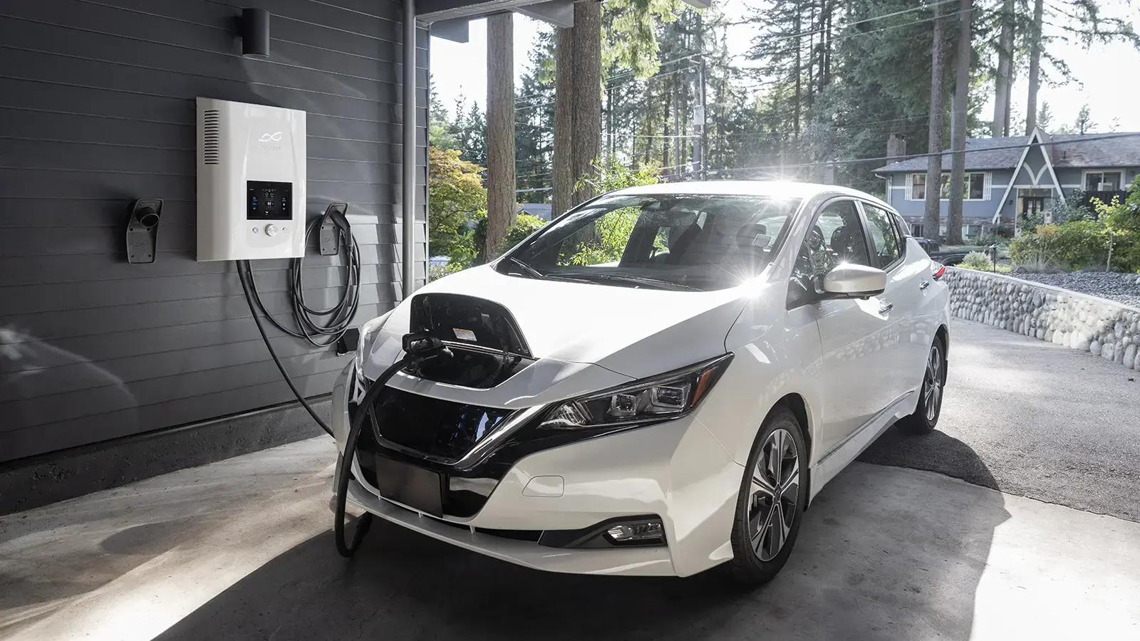 Un Nissan Leaf blanco cargando en casa en el garaje
