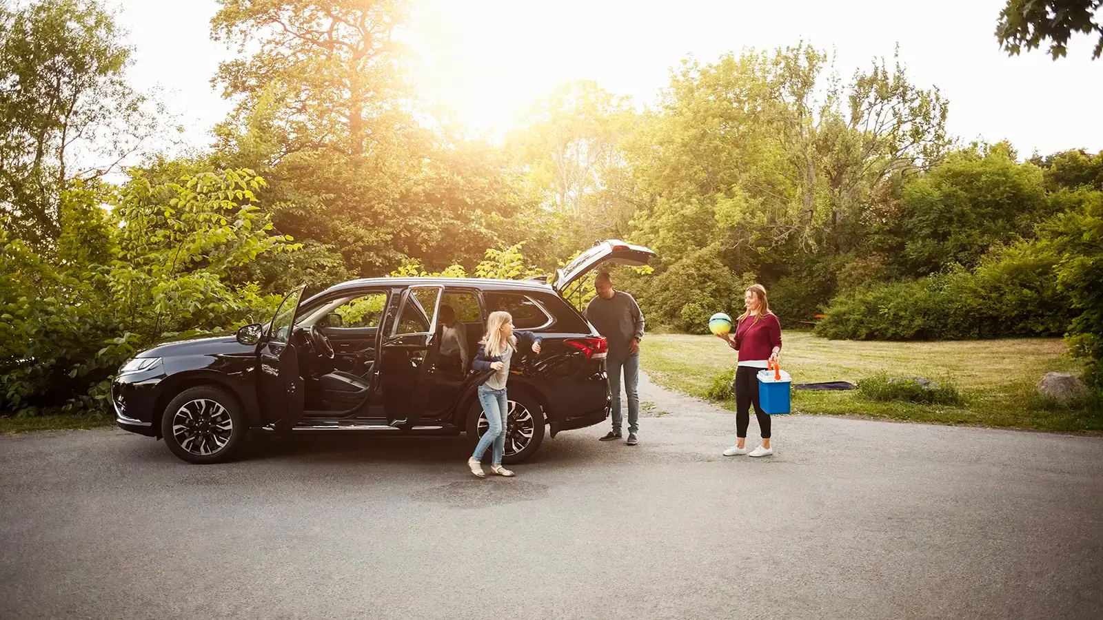 Coche verde estacionado con la familia descargando el vehículo