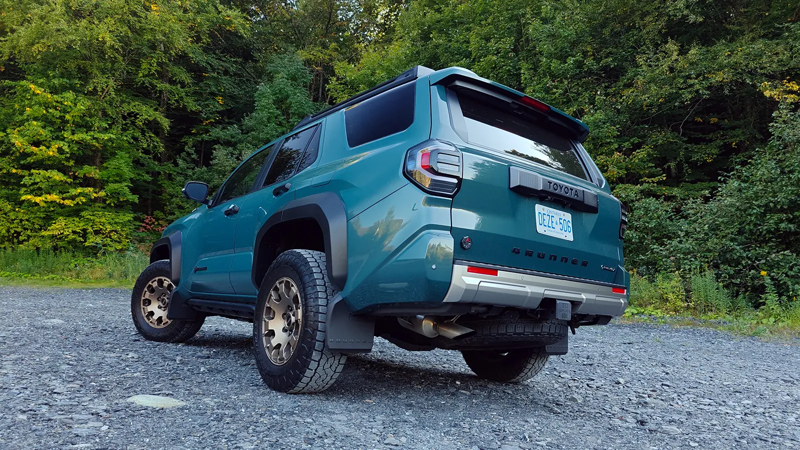 A blue 2025 Toyota 4Runner Trailhunter rear 3quarter view in the forest