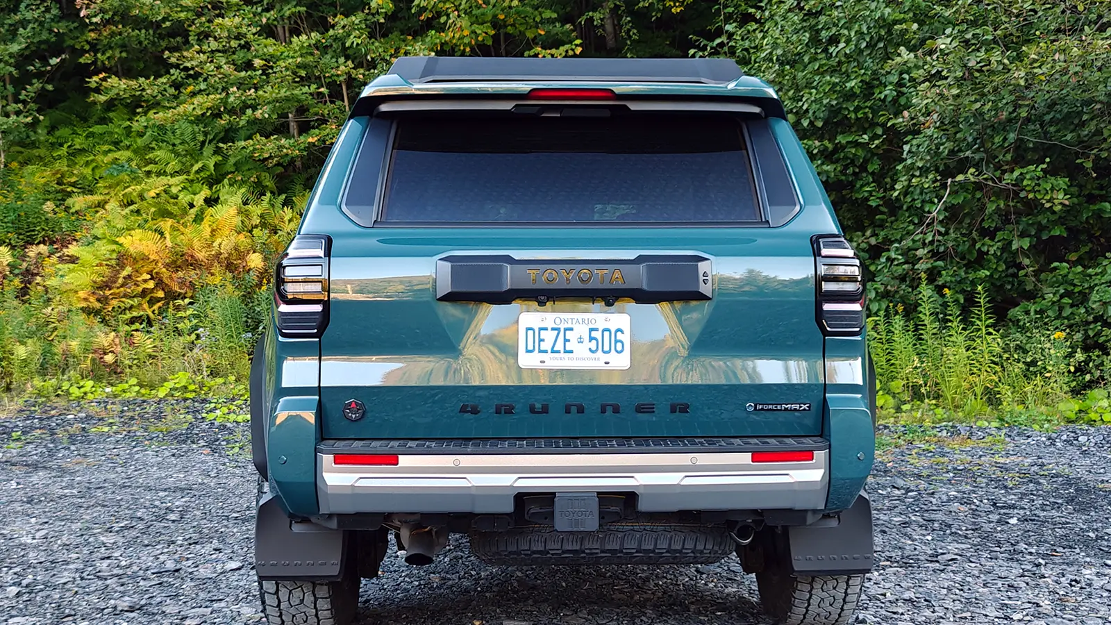 A blue 2025 Toyota 4Runner Trailhunter rear view in the forest
