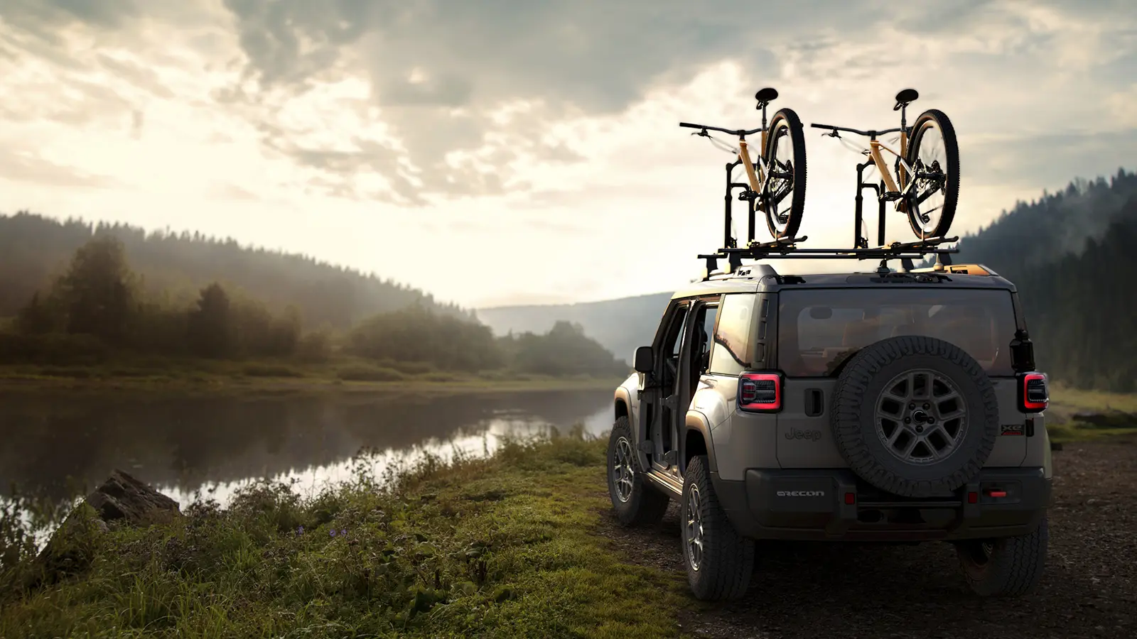 A silver 2026 Jeep Recon EV with bikes on top in a scenic river