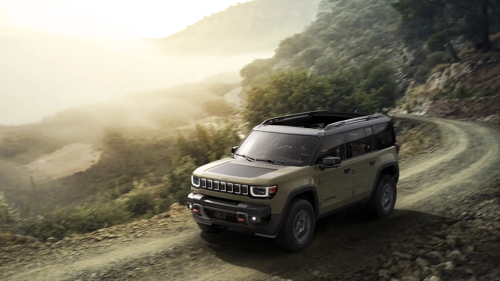A tan 2026 Jeep Recon EV on a scenic mountain route