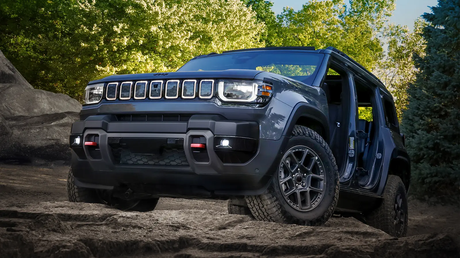 A dark blue 2026 Jeep Recon EV climbing rugged rocks