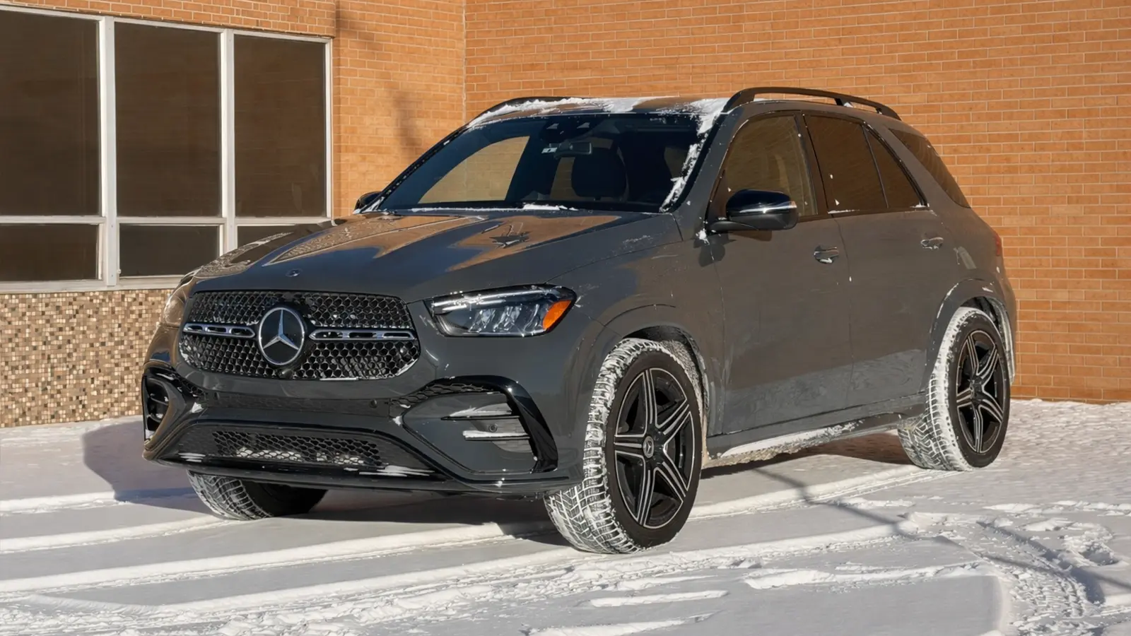 A dark gray 2026 Mercedes-Benz GLE450 4matic parked near a building in the snow