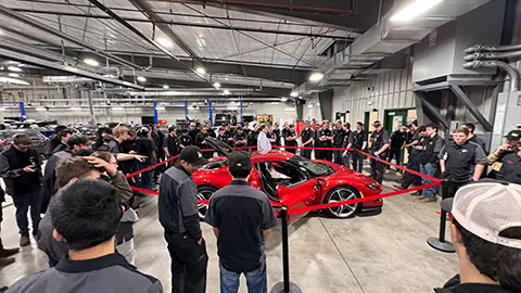 Técnicos automotrices de pie alrededor de un Ferrari en un almuerzo