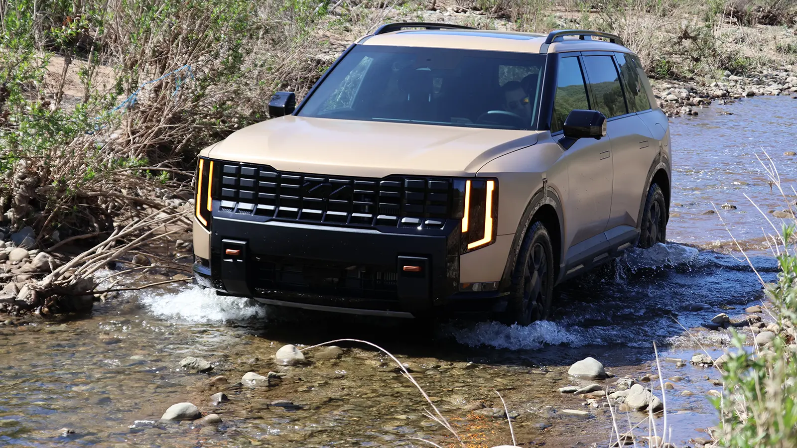 A 2027 Kia Telluride front view driving up a river