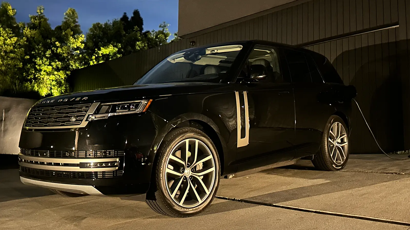 A black 2025 Land Rover Range Rover SE PHEV Review parked in front of a house