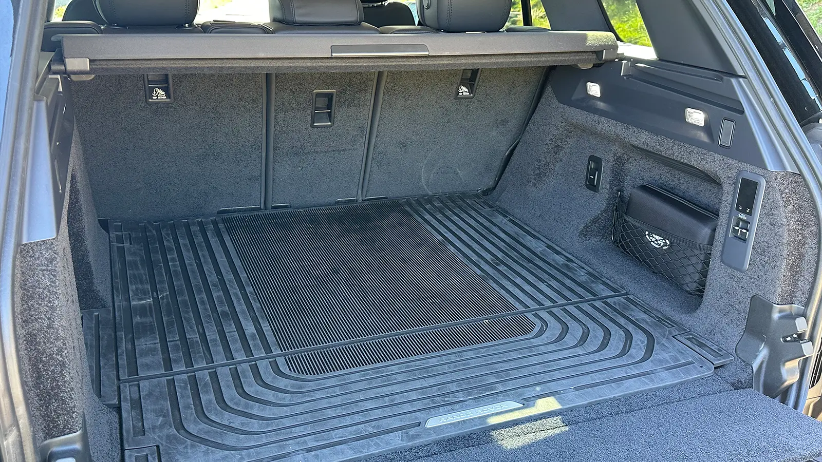 A black 2025 Land Rover Range Rover SE PHEV Review trunk rear view with lid open