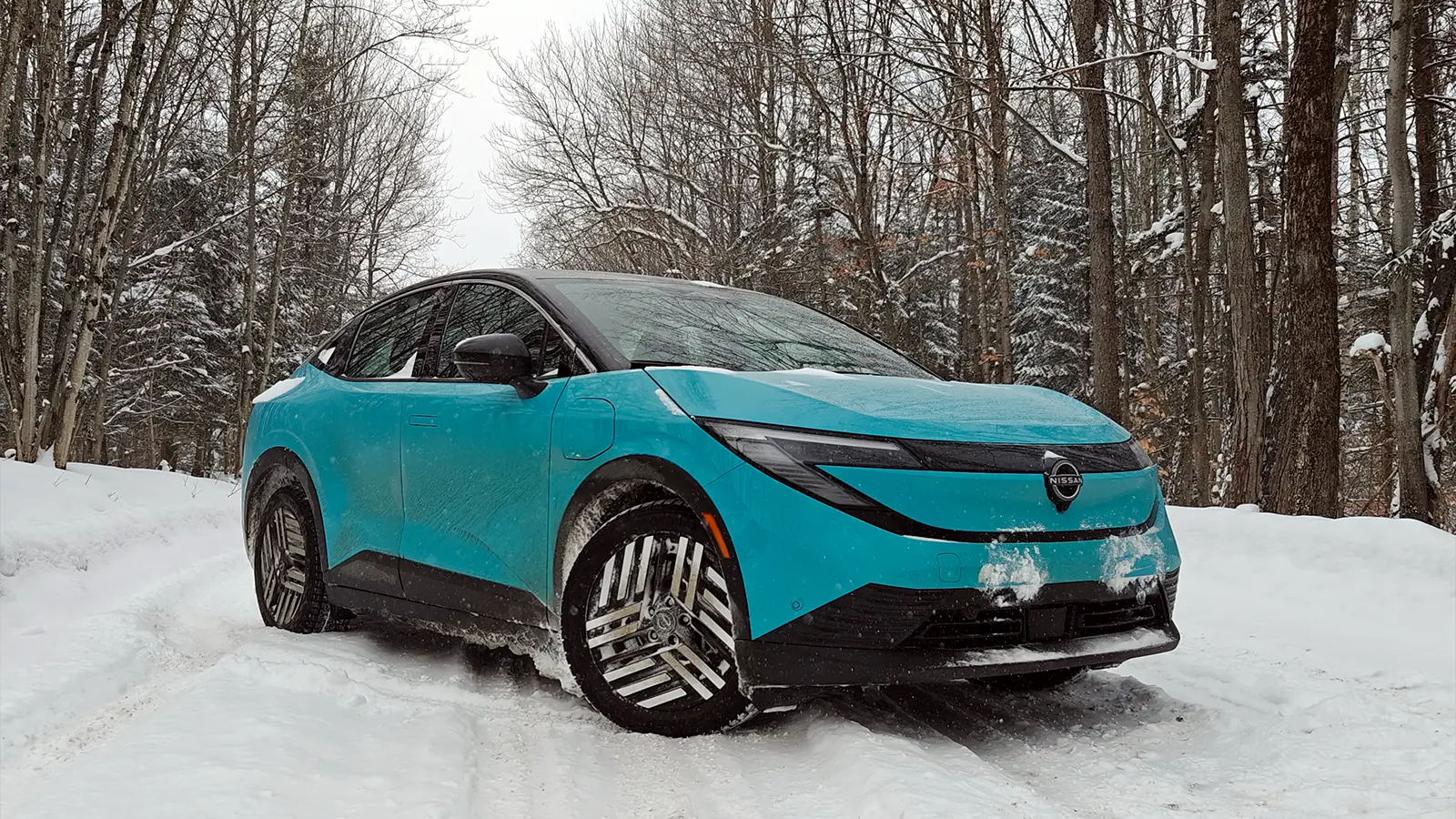 Un Nissan Leaf 2026 verde azulado en invierno: vista frontal de tres cuartos
