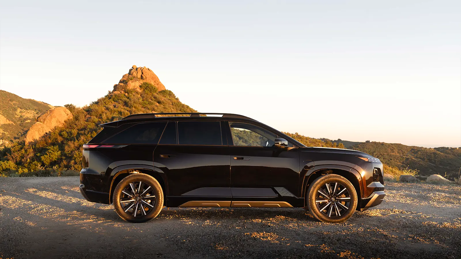 A black 2027 Subaru Getaway side view on a mountain