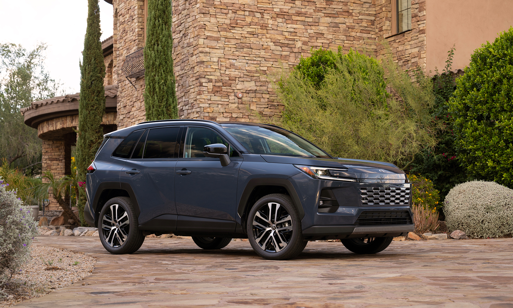 A dark blue 2026 Toyota Rav4 hybrid exterior three-quarter front view in front of Tuscan house