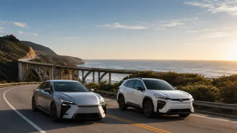 A Lexus and Subaru driving next to each other on scenic highway.