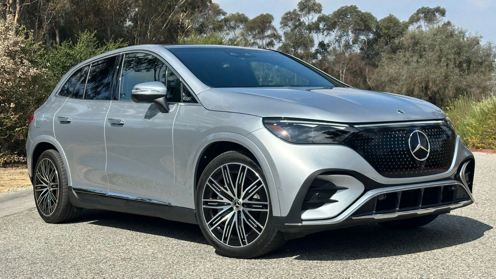 A silver 2026 Mercedes-Benz EQE 320+ SUV parked in front of a wispy tree