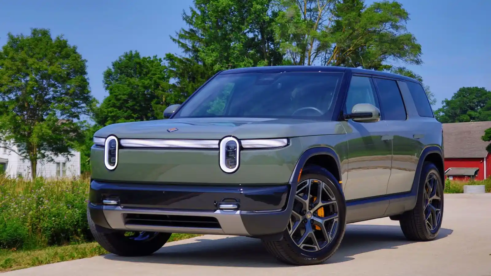 Un Rivian R2 2027 de color verde Catalina Cove aparcado cerca de un prado verde y cubierto de hierba