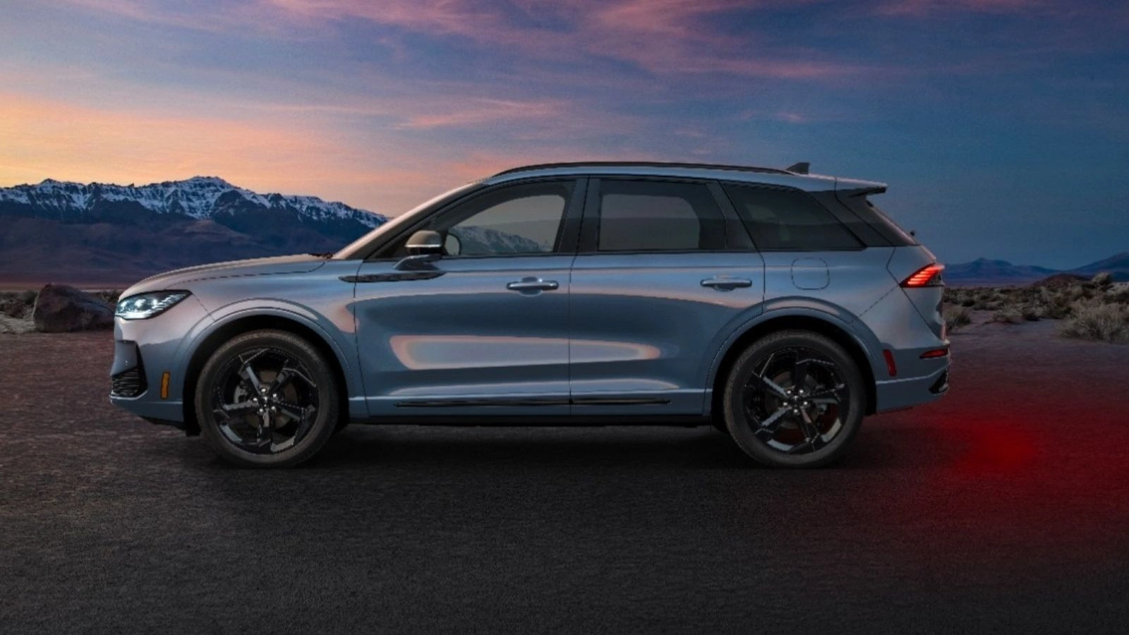 Vista de perfil del Lincoln Corsair Hybrid 2027 en color plata, con un terreno montañoso de fondo al atardecer.