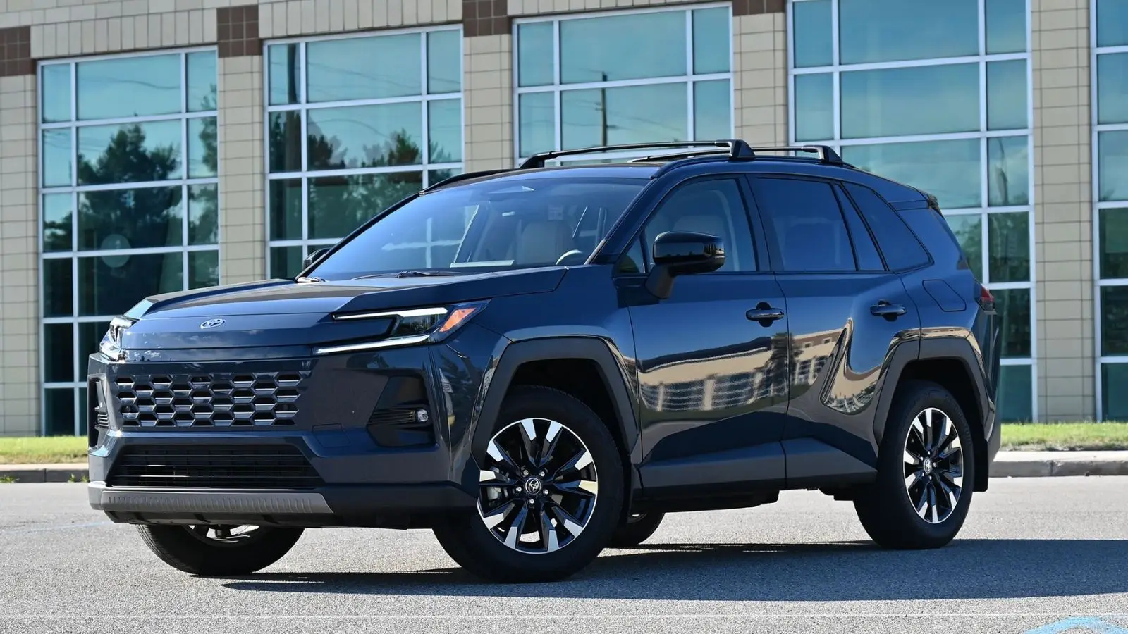 2026 Toyota RAV4 angled sitting in a parking lot in front of a mirrored building