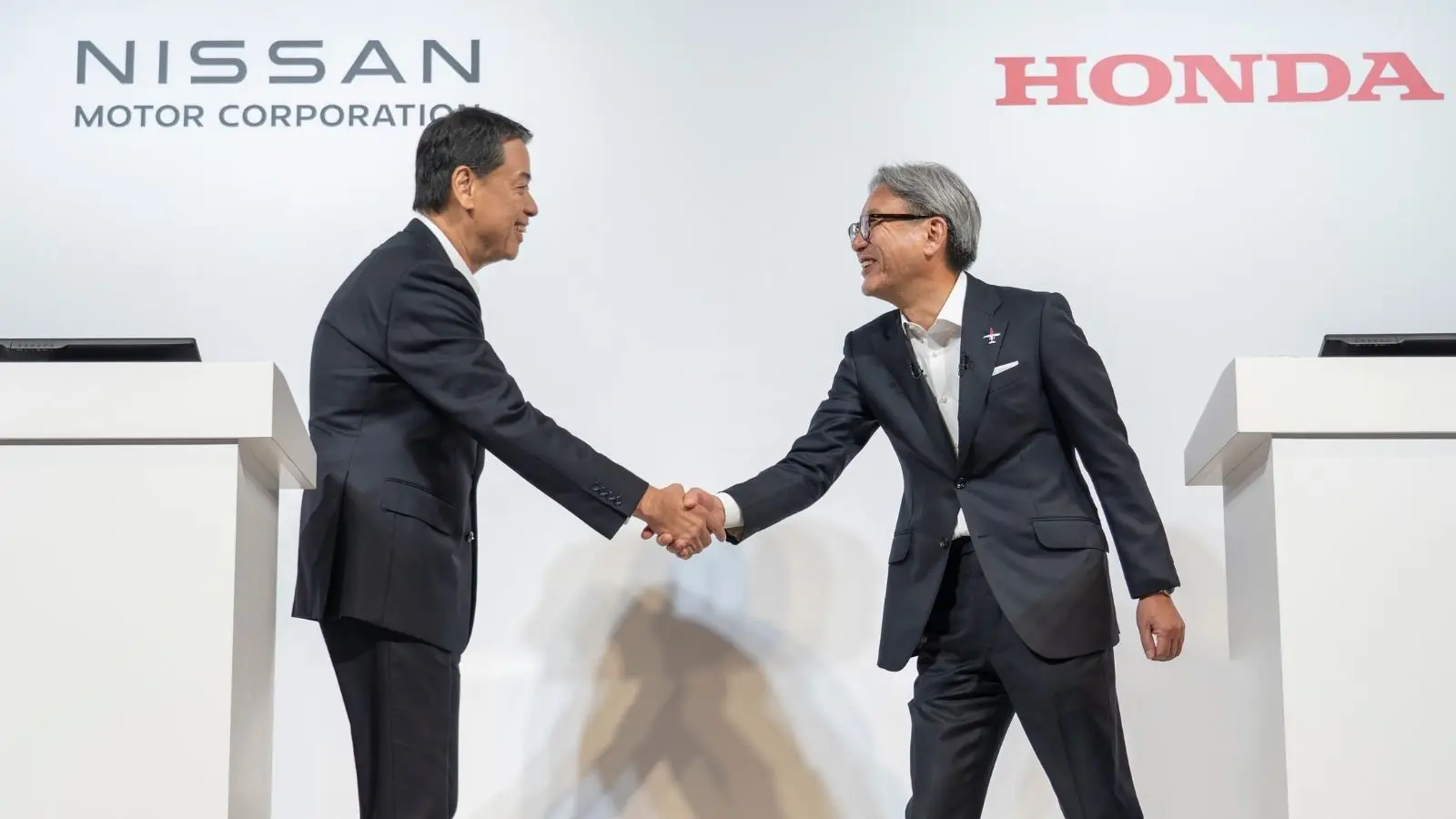 Photo from Nissan and Honda Joint Press Conference of Executives shaking hands