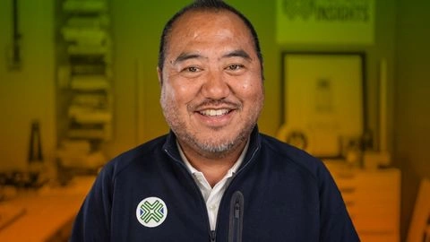 Tu Lee, Founder of Sino Auto Insights, pictured in front of a green and orange background.