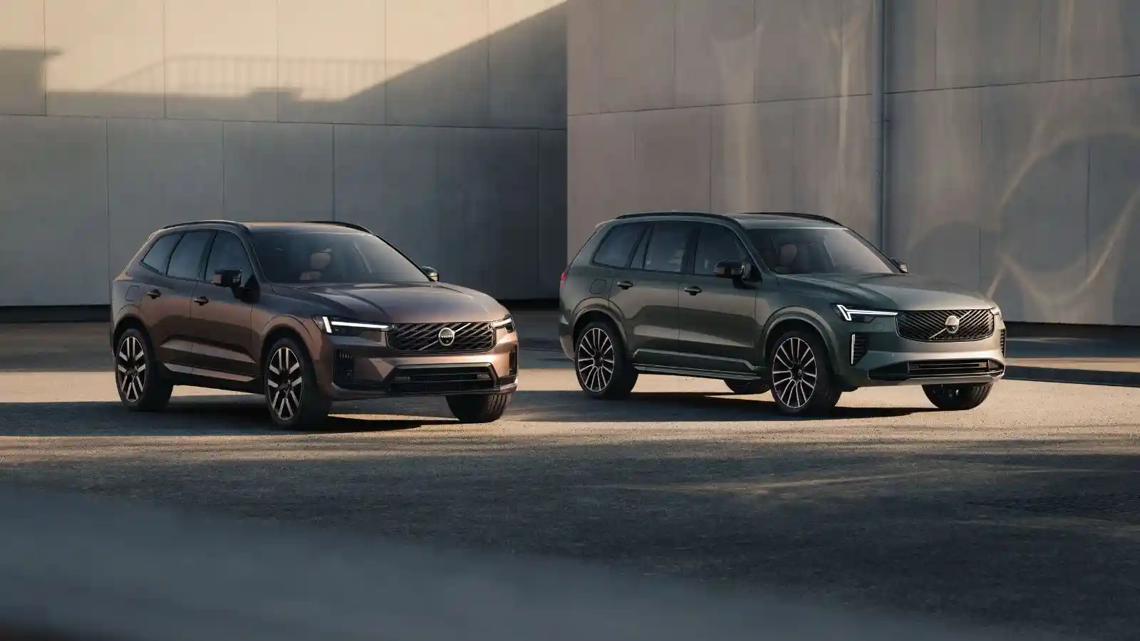 The all new Volvo XC60 and Volvo XC90 parked angled in front of a concrete building