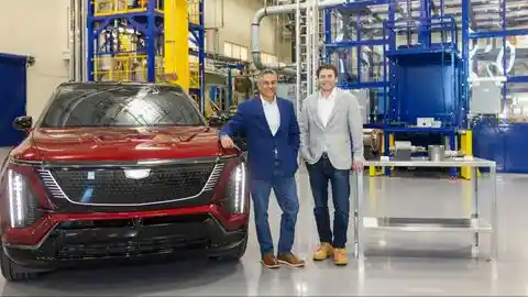 Shilpan Amin, Global Chief Procurement and Supply Chain Officer at General Motors, and James Litinsky, Chairman & CEO of MP Materials, stand beside Cadillac EV parked inside a MP Materials plant.