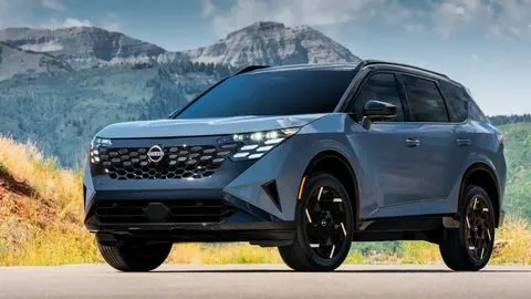 Blue 2027 Nissan Rogue Hybrid parked at an angle with a mountainous terrain in the background