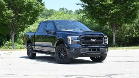 A 2026 Ford F-150 Powerboost Hybrid is parked at an angle in a parking lot against a landscaped background
