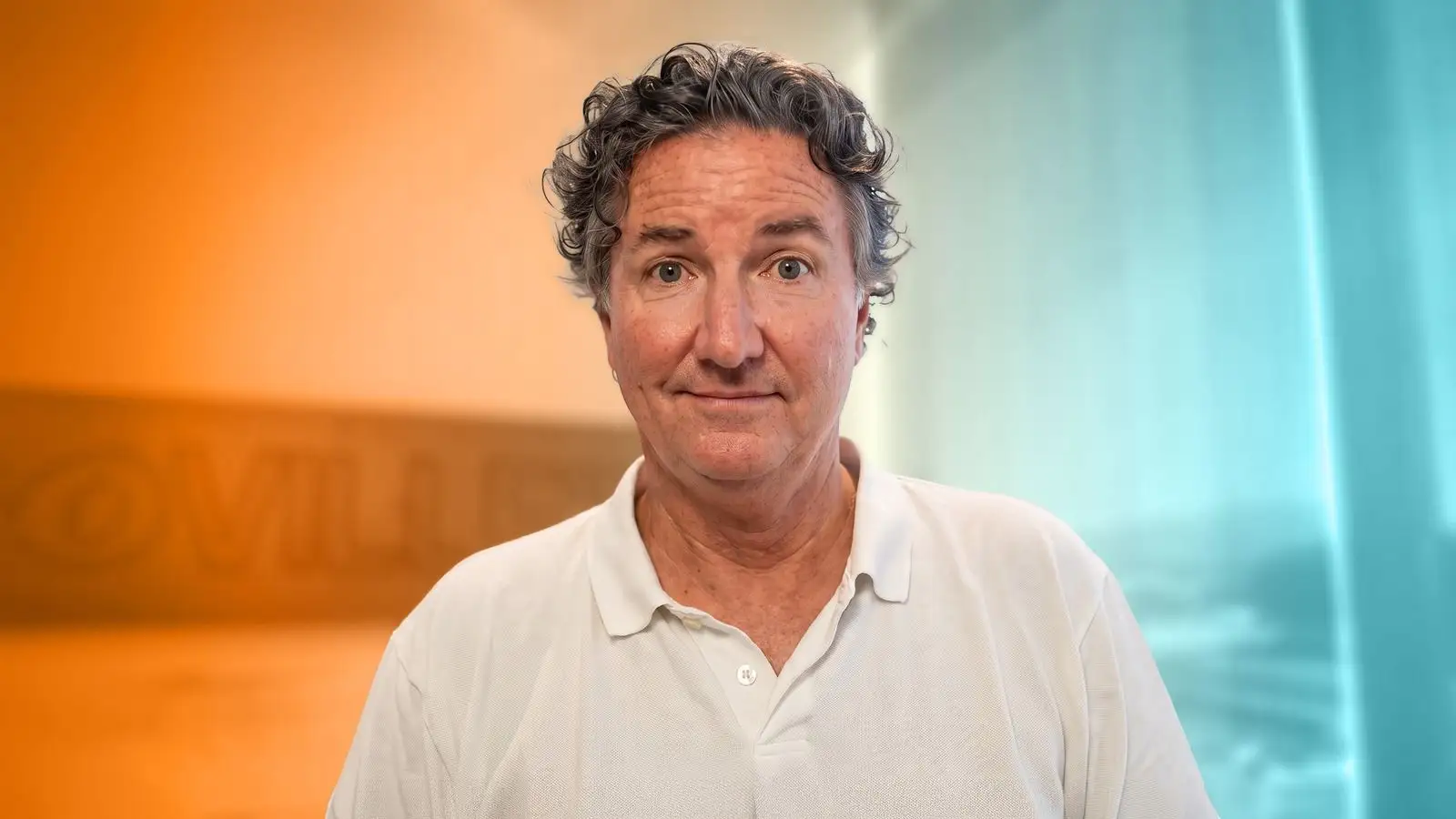 Headshot of James Bell, Kia America's Head of Corporate Communications, on a orange and blue faded background