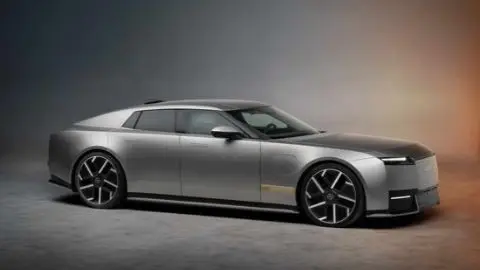 A side angle view of a silver Jaguar Type 01 on an orange to grey background.