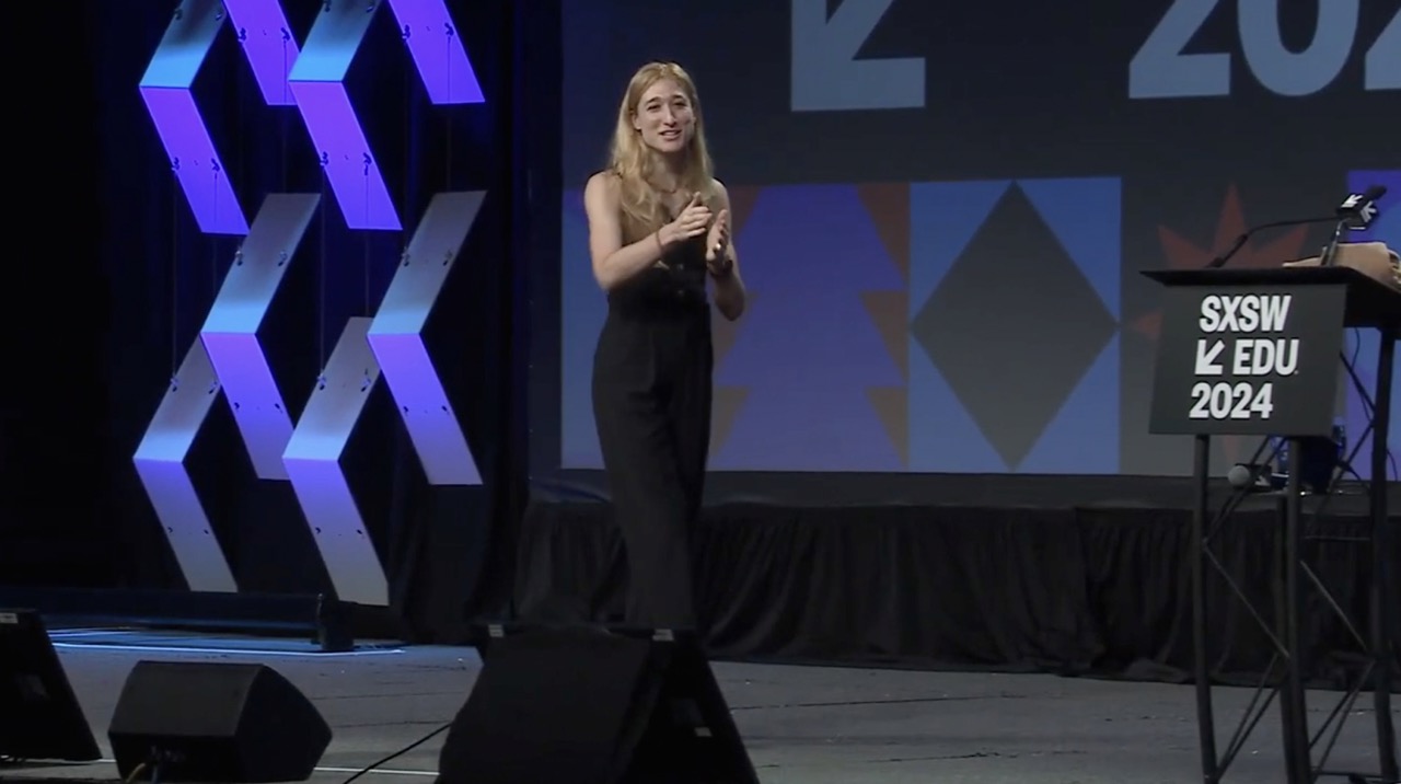 Woman in a black dress giving a presentation on stage at SXSW EDU 2024 event.