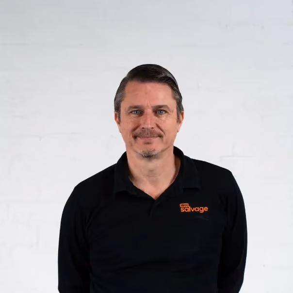 Middle-aged man in black polo shirt with salvage logo smiling