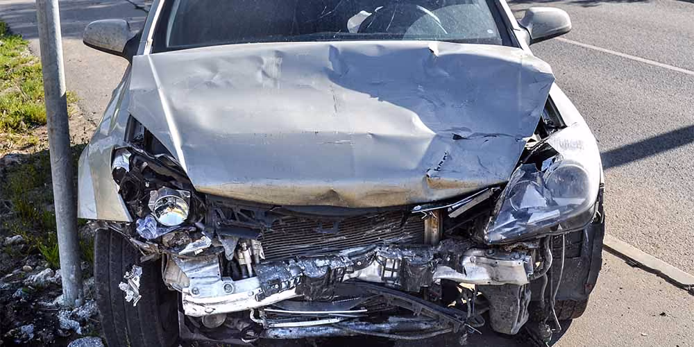 Grey car with a totally smashed front bumper and engine block.