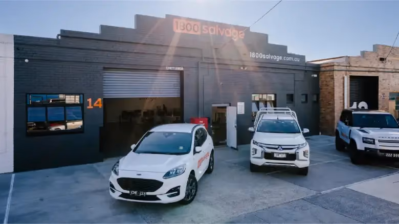 1800 Salvage workshop exterior with branded vehicles parked outside the building.