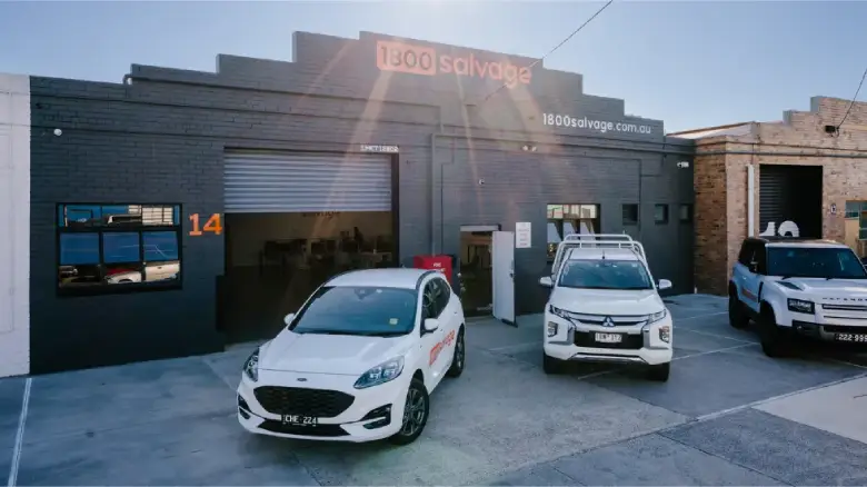 1800 Salvage workshop exterior with branded vehicles parked outside the building.