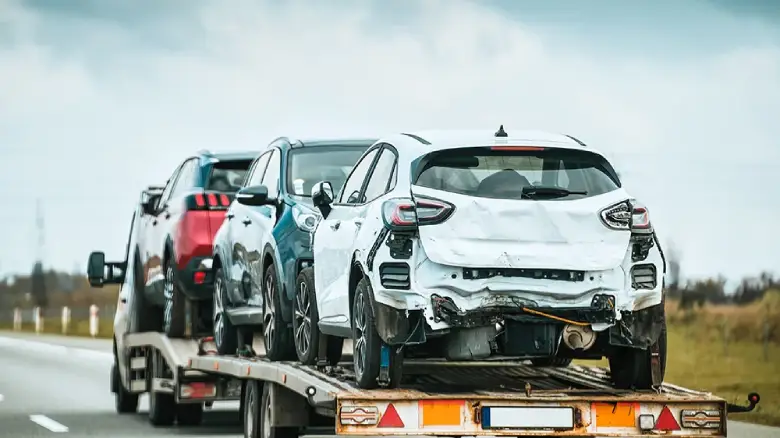 Tow truck carrying damaged vehicles in Darwin, representing free car removal services that buy cars for cash in any condition.