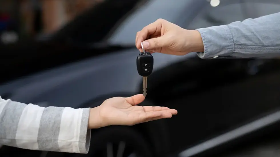 Person handing over car keys in Darwin, showing the process to sell your car quickly through a hassle free car buying service.