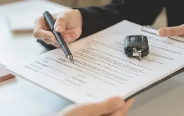 Person signing paperwork with car keys on top of the document, transferring ownership when selling an unregistered car in Hobart.