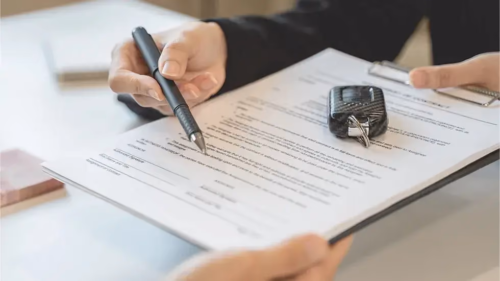 Person signing paperwork with car keys on top of the document, transferring ownership when selling an unregistered car in Hobart.