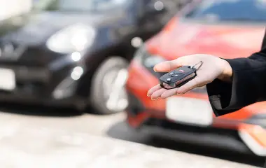 Person ready to sell my car in Hobart holding car keys with vehicles parked in the background.