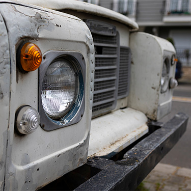 Vintage white Land Rover with round headlight and orange signal lamp