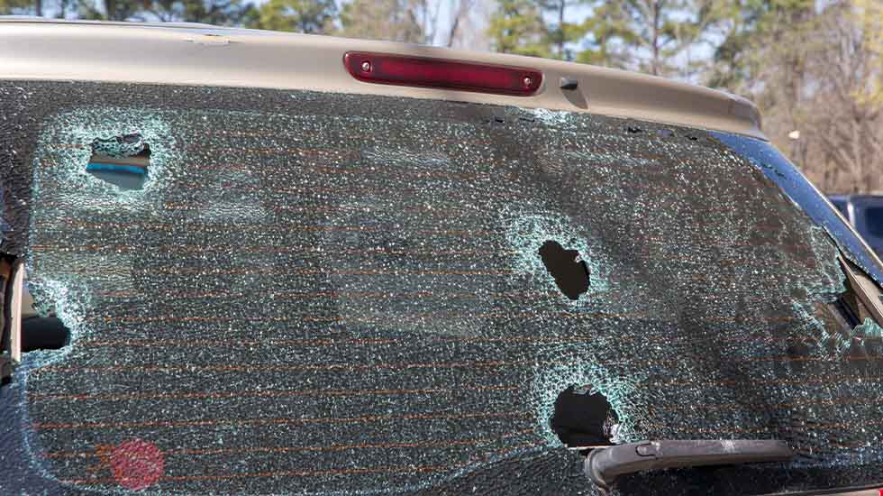 Shattered rear car window with multiple bullet holes